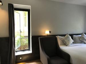 a bedroom with a bed and a chair and a window at Hotel Noir in Chiang Mai