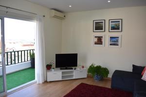 a living room with a flat screen tv on a white wall at Varanda do jardim in Belmonte