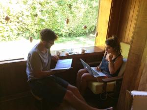 two people sitting in a window with their laptops at Lucky's Hostel in Pucón