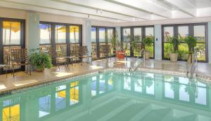a swimming pool in a building with tables and chairs at Capes Hotel in Virginia Beach