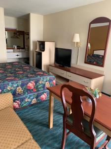 a hotel room with a bed and a table and a mirror at Suite Stay - Talladega in Talladega