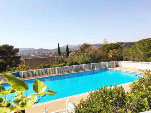 a large blue swimming pool with trees and mountains in the background at Villa la Grande Bastide piscine et tennis collectif in Cassis