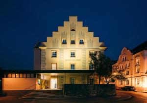 un grande edificio bianco con un orologio sopra la notte di Central City Hotel a Füssen