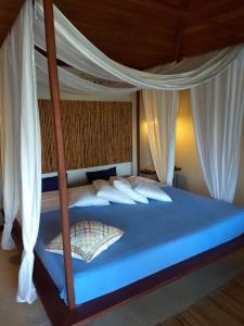 sypialnia z niebieskim łóżkiem z białymi zasłonami w obiekcie Pousada Residencia Duna Paraiso w mieście Maceió