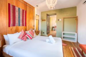 a bedroom with a large white bed with colorful pillows at Selina Saphi Cusco in Cusco