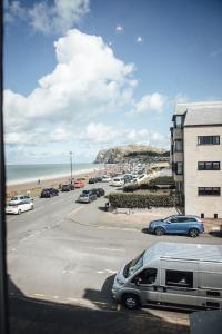 a parking lot with cars parked next to the beach at Carmel House in Llandudno