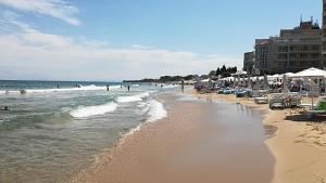 a beach with chairs and umbrellas and the ocean at 2 rooms apartment in the center in Nesebar