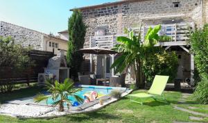 un patio trasero con piscina con silla y sombrilla en PAUSE ROMANTIQUE EN PAYS BRAYAUD en Châtel-Guyon
