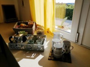 una mesa con tazas y tazas junto a una ventana en La Casetta en Vittorio Veneto