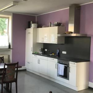 a kitchen with white cabinets and a purple wall at Gästehaus Sandra in Sulzbach-Rosenberg