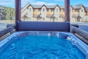 a hot tub on a patio with a building in the background at Saddle Ridge Townhome I-5 in Big Sky
