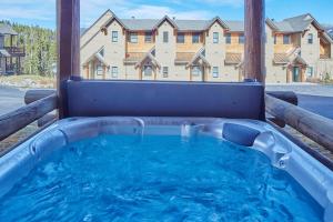 una bañera de hidromasaje en un patio con un edificio al fondo en Saddle Ridge Townhome I-5, en Big Sky