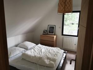 a bedroom with a white bed and a window at La cabane Des Pins... in Quend