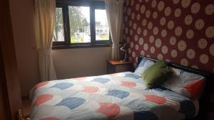 1 dormitorio con 1 cama con edredón y ventana en 3 bed room house, en Aberdeen
