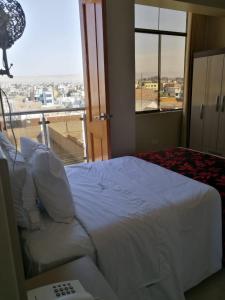 a bedroom with a bed with a view of a city at Hotel Spa Machupicchu in Tacna