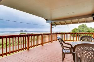 a deck with a table and chairs and the beach at Falcon's Nest in Twin Rocks