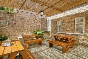 a patio with wooden picnic tables and a stone wall at Mediterranean Holiday House & Apartments in Kotor