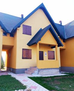 une maison jaune avec un toit bleu dans l'établissement Apartments Darija, à Žabljak