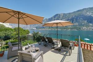 un patio con sillas, mesas y sombrillas en Mediterranean Holiday House & Apartments, en Kotor