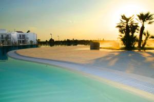 an empty swimming pool with palm trees and the sunset at I GIARDINI DI ZEUS in Metaponto