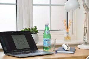 a laptop computer sitting on a desk with a bottle of water at Glebelands in West Monkton