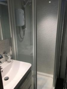 a bathroom with a shower and a white sink at Woodland View - a place to escape in Swynnerton
