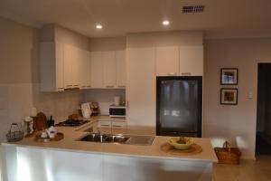 a kitchen with white cabinets and a sink at Gone to Barossa in Tanunda