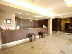 a lobby with a counter and two benches in a building at HOTEL ROUTE-INN Ota Minami -Route 407- in Ota