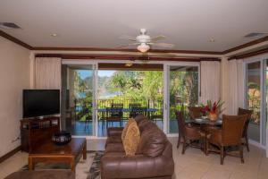 Sala de estar con sofá, TV y mesa en Los Suenos Resort Bay Residence 7C, en Herradura