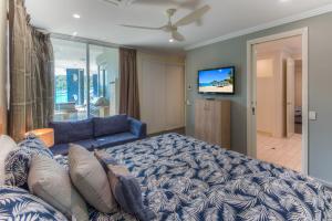 - une chambre avec un lit bleu et un canapé dans l'établissement Pavillions on Hamilton Island by HIHA, à Île Hamilton