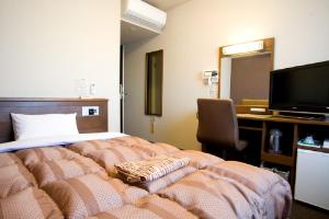 a bedroom with a bed and a desk and a television at Hotel Route-Inn Nanao Ekihigashi in Nanao