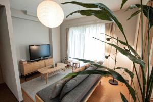 a living room with a couch and a television at UCHI Living Stay Otaru Suitengu in Otaru