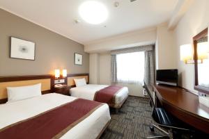 鹿児島市にあるホテル法華クラブ鹿児島のベッド2台、薄型テレビが備わるホテルルームです。