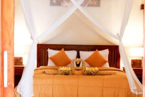 a bedroom with a canopy bed with orange pillows at Bahari Villa Tejakula in Tejakula