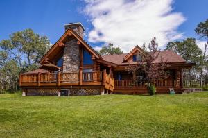 una casa de madera con una gran terraza en el césped en Lake Fork Lodge, en McCall