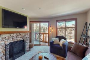 a living room with a fireplace and a tv at Powderhorn Lodge 311: Poppy Suite in Solitude