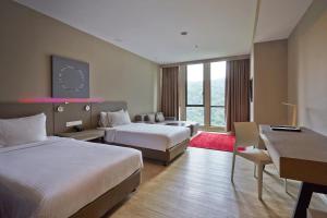 八打灵再也Qliq Damansara Hotel的有两张床和一张书桌的酒店房间