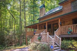 a wooden cabin in the woods with a large porch at Bearfoot Retreat in Waldens Creek