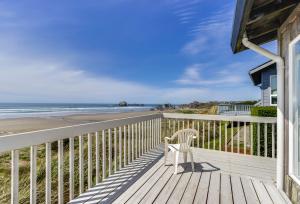 una silla blanca sentada en una terraza con vistas a la playa en Spindrift Oceanfront Home, en Bandon