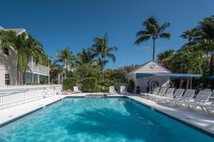 a swimming pool with chairs and palm trees at Shipyard Perch in Key West