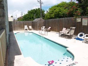 - une piscine dans un jardin avec des chaises et une clôture dans l'établissement Beverly Condos #0003, à South Padre Island