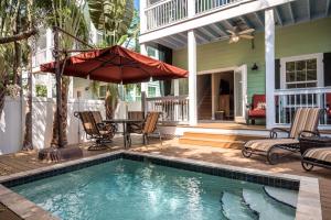 uma piscina com cadeiras e um guarda-sol ao lado de uma casa em Casa Atlantic em Key West