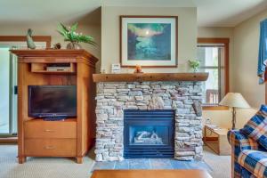 a living room with a stone fireplace and a tv at Powderhorn Lodge 223: Pennyroyal Suite in Solitude