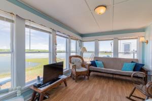 a living room with a couch and a tv and windows at The Eastern Avenue Cottage in Wells Beach