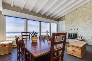a dining room with a table and a view of the ocean at Spindrift Oceanfront Home - The Helm in Bandon