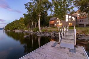 a wooden dock leading to a house on a lake at Lodge at Moosehead Lake in Greenville Junction