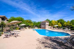 einen Pool mit Stühlen, Tischen und Sonnenschirmen in der Unterkunft Vistoso Casitas Golf II #210B in Tortolita