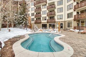 a swimming pool in front of a building in the snow at Passage Point 207 in Copper Mountain