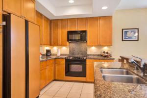 a kitchen with wooden cabinets and a sink and a refrigerator at Waikoloa Colony Villas #1306 in Waikoloa