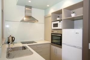 a kitchen with a sink and a microwave at Korora Bay Village Resort in Coffs Harbour